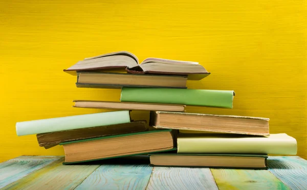 Colorful hardback books on yellow background