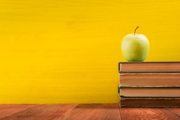 Stack of colorful hardback books on yellow background.