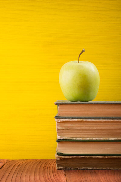 Stack of colorful hardback books on yellow background.