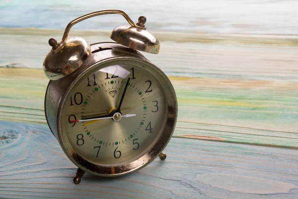 Reloj despertador retro dorado sobre fondo de madera claro con espacio para copiar — Foto de Stock