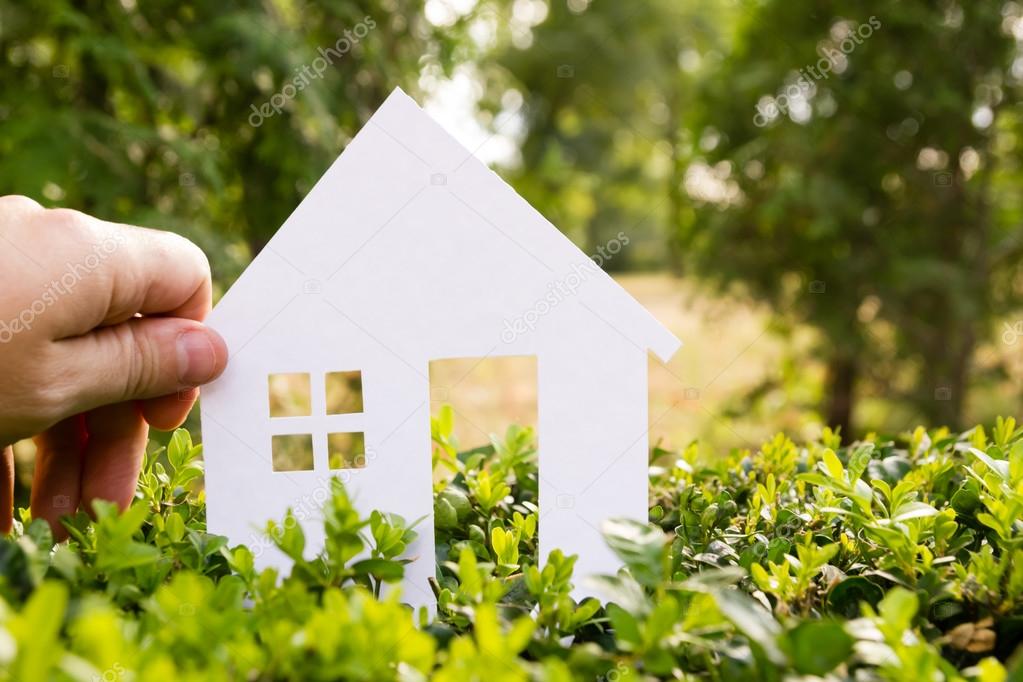 Real Estate Concept Paper model house against green grass background. Ecological building. Top view.