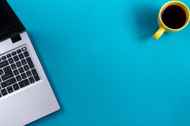 Ofis tablo Masası dizi renkli malzemeleri, beyaz boş not defteri, Kupası, kalem, pc, buruşuk kağıt, ile mavi arka plan üzerinde çiçek. Metin için en iyi görünüm ve kopya yer