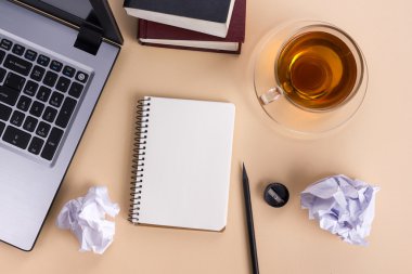 Ofis tablo büro malzemeleri, beyaz boş not defteri, Kupası, kalem, pc, buruşuk kağıt, ahşap arka plan üzerinde çiçek. Üstten Görünüm