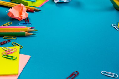 Ofis tablo Masası dizi renkli malzemeleri, beyaz boş not defteri, Kupası, kalem, pc, buruşuk kağıt, ile mavi arka plan üzerinde çiçek. Metin için en iyi görünüm ve kopya yer