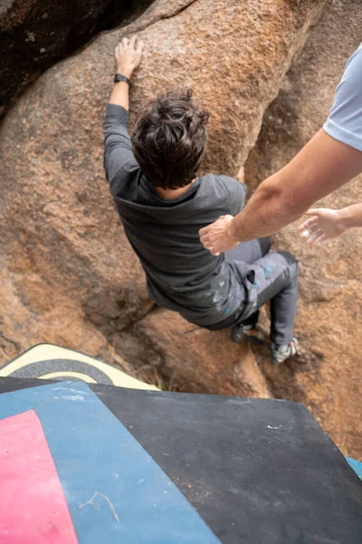 Erkek bir dağcı altında kazayla bir kayaya tırmanmaya çalışıyor.