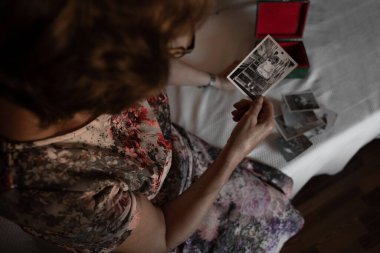 Çocukluk fotoğraflarına bakan tanınmayan yaşlı bir kadın.