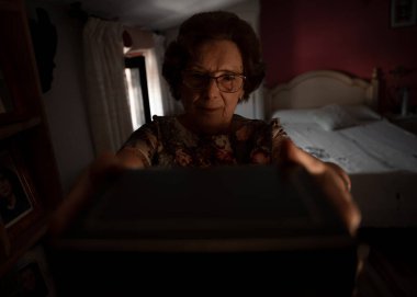 Nostaljik yaşlı kadın yatak odasındaki raflardan bir kutu alıyor.