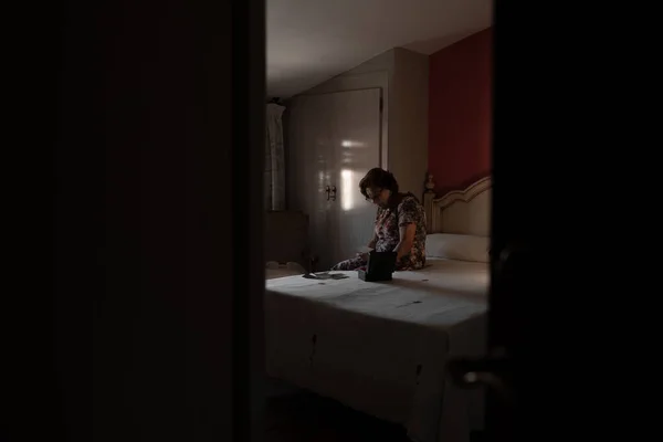 Yatakta oturmuş fotoğraflara bakan nostaljik yaşlı kadın.