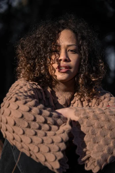 Güzel kıvırcık kız ellerini çapraz yapıp kameraya bakıyor.