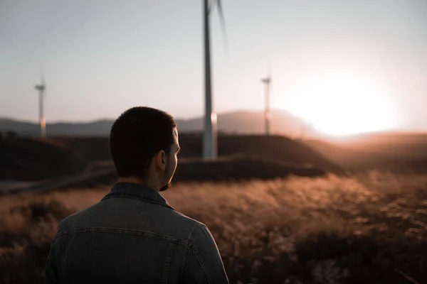 İnsan gün batımını izlerken düşünüyor. Etrafı yel değirmenleriyle çevrili.