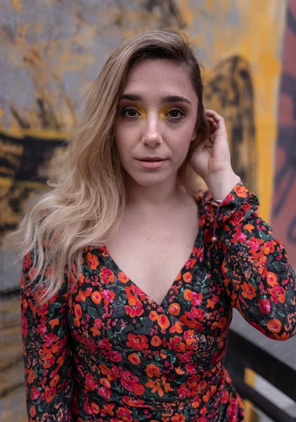 Modelo joven rubia posando tocándose el pelo delante de una pared de graffiti amarillo —  Fotos de Stock