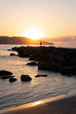Güneş doğarken balıkçı siluetinin dikey fotoğrafı
