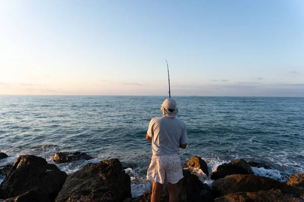 Viejo pescando junto al mar al amanecer — Foto de Stock