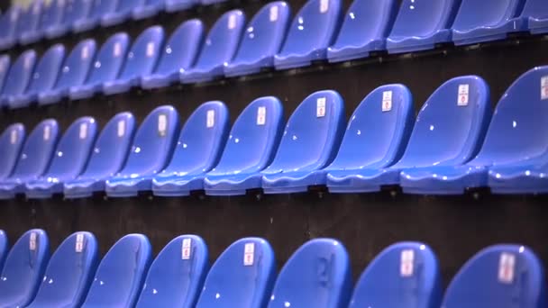 Chaises bleues humides vides sur la tribune d'un stade de football sous la pluie — Video
