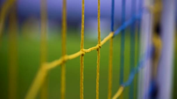 Крупним планом жовтий синій футбольний м'яч сітка трясеться на фіолетове небо і легка вежа — стокове відео