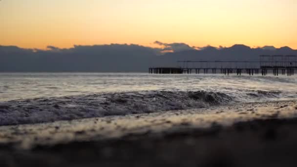 Εστίαση από τη θάλασσα στο κύμα που ξεχύνεται πάνω από την παραλία στο ηλιοβασίλεμα ή την ανατολή του ηλίου — Αρχείο Βίντεο