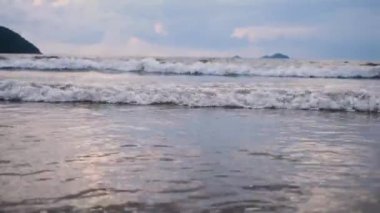 Slow motion shot of seawaves rolling towards the shore during sunset.
