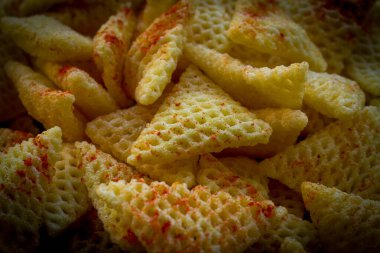 Üzerine kırmızı biber tozu serpiştirilmiş üç köşeli kızarmış Hint atıştırmalıkları..