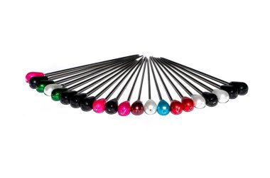 Beyaz üzerinde izole edilmiş sığ alan derinliğine sahip çok renkli inci başlık iğnelerinin sıralanması.