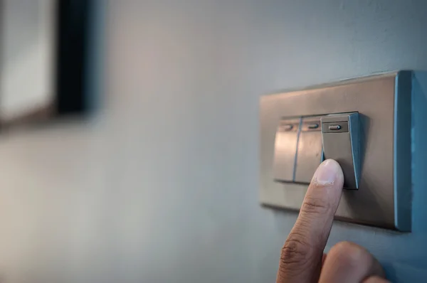 Finger is turning on a light switch.