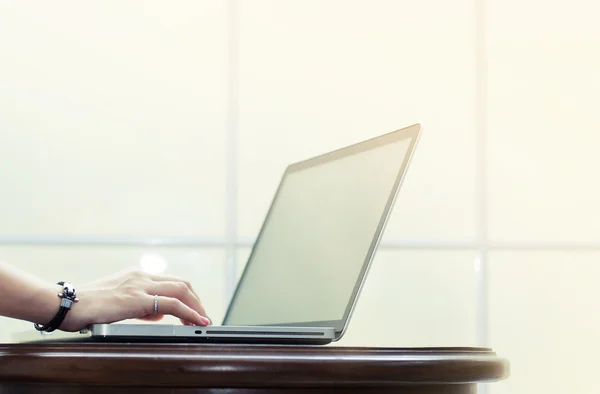 A mão está digitando no laptop na mesa de madeira no parapeito da janela branca — Fotografia de Stock