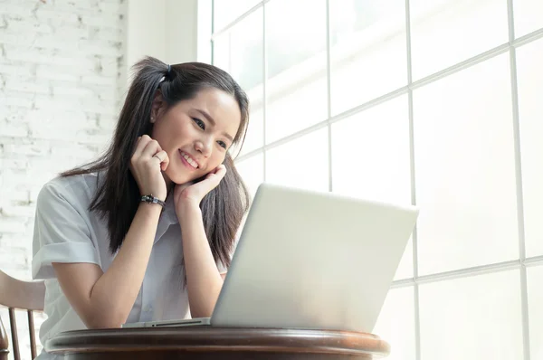 Menina asiática feliz e sorriso em seu trabalho com seu laptop — Fotografia de Stock