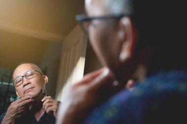 Yaşlı adam banyoda sakal tıraş oluyor