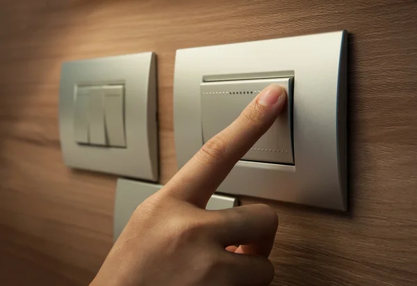 Dedo está ligando um interruptor de luz cinza . — Fotografia de Stock