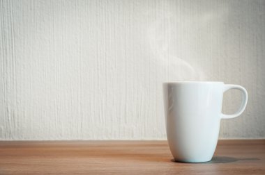 Tahta masada beyaz bir fincan kahve.