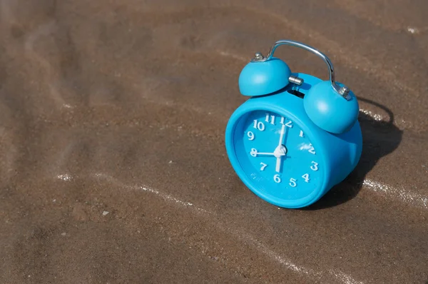 Vista superior del reloj despertador retro en la arena de la playa del mar . — Foto de Stock