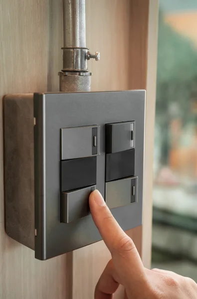 Finger is turning on a grey or black metallic light switch — Stock Photo, Image