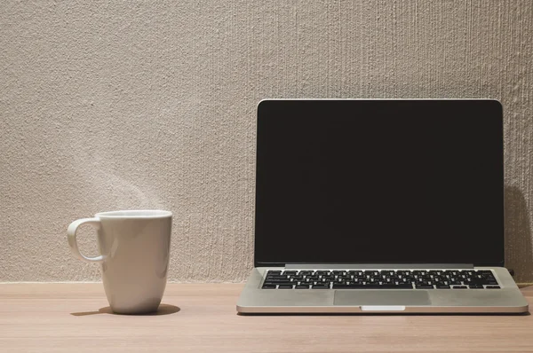 黑色的空白屏幕和白色杯咖啡的笔记本电脑 — 图库照片