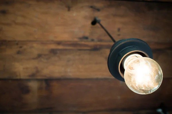 Decorative antique light bulb with old wooden ceiling background — Stock Photo, Image