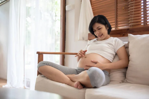 Giocoso Asiatico Donna Seduta Divano Toccante Pancia Con Mano Dita — Foto Stock