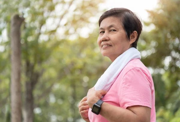 Portrait of Asian Senior woman smiling while doing exercise workout at park outdoor with copy space, Positive Emotion. Relaxation of Healthy Carefree Mature female