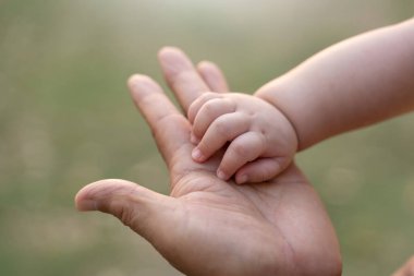 Asyalı Baba, dışarıda minik bebek ellerini birbirine dokundurup tutuyor..