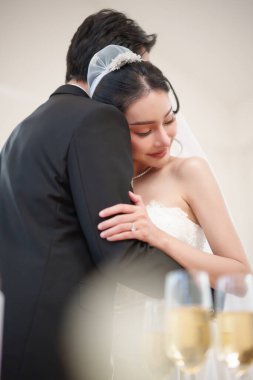 Neşeli Asyalı çift düğünlerinde birbirlerine sarılıyorlar, zarif ve romantik bir ortamda aşkı ve birlikteliği kutluyorlar..