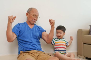 Mutlu Asyalı büyükbaba torunuyla evde eğleniyor. Kahkaha, neşe ve yakın aile ilişkisinin tadını çıkarıyor..
