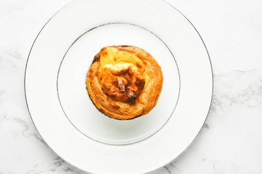 Mermer masada beyaz tabakta taze pişmiş yumurtalı tart resmi. Ünlü Macao, Malezya ve Portekiz atıştırmalıkları.