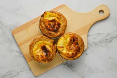 Mermer masada ahşap tahtaya dizilmiş üç yeni pişmiş yumurtalı tart. 