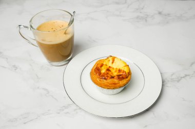 Taze pişmiş yumurtalı tart ve tabakta sütlü kahve.