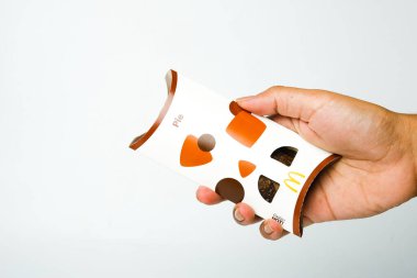 Beyaz arka planda yeni McDonald çikolatalı turtayı tutan bir el resmi..