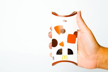 Beyaz arka planda yeni McDonald çikolatalı turtayı tutan bir el resmi..