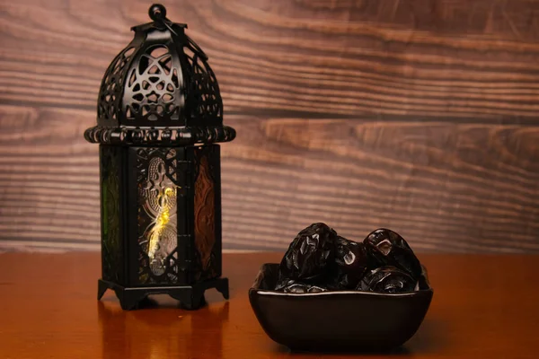 Ahşap arka planda fener bulunan ajwa tarihlerinin seçici odak noktası. 