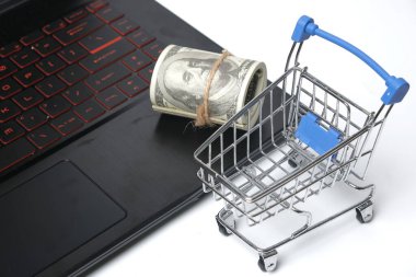 Oyuncak arabasının seçici odak fotoğrafı ve online alışveriş konsepti için dizüstü bilgisayarlı sahte para. Çevrimiçi alışveriş artık Covid-19 salgını sırasında bir eğilim