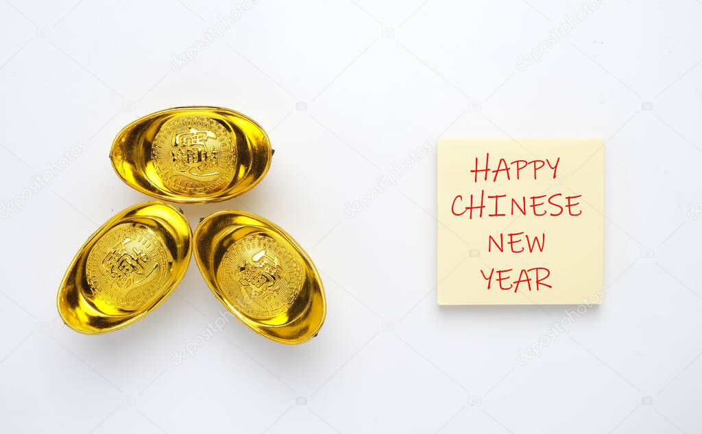 A picture of Happy Chinese New Year on notepad and golden ingot or 
