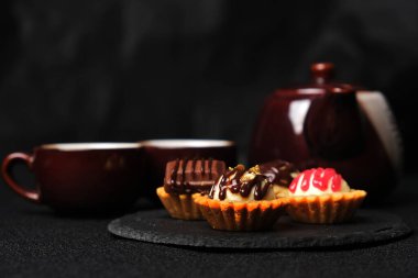 Seçici odak noktası, arka planda çay fincanı ve çaydanlık ile ev yapımı çikolatalı peynirli tart.