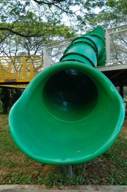 Halk parkındaki büyük yeşil kaydırak çıkışının seçici odak noktası.