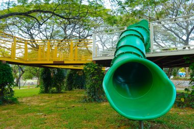 Halk parkındaki büyük yeşil kaydırak çıkışının seçici odak noktası. 