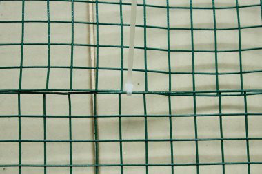 Hayvan eskriminde kullanılan kablo kravatlı PVC kaplı tel örgülü bir resim..